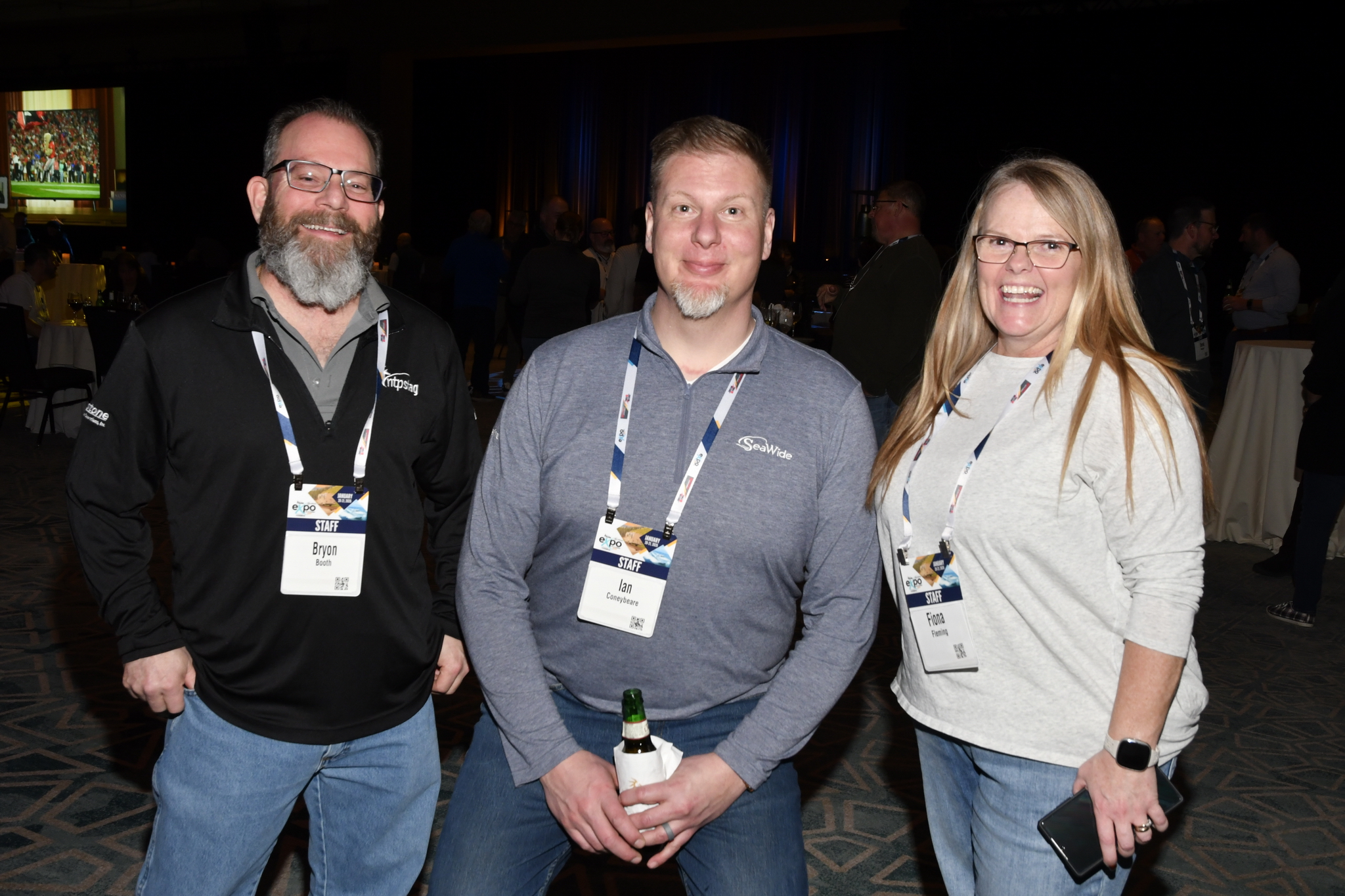 six-foot four Ian Coneybeare, centre, knelt down to eye level to schmooze with team mates Bryon Booth and Fiona Fleming at the NTP-Stag SeaWide Expo opening reception in Orlando.