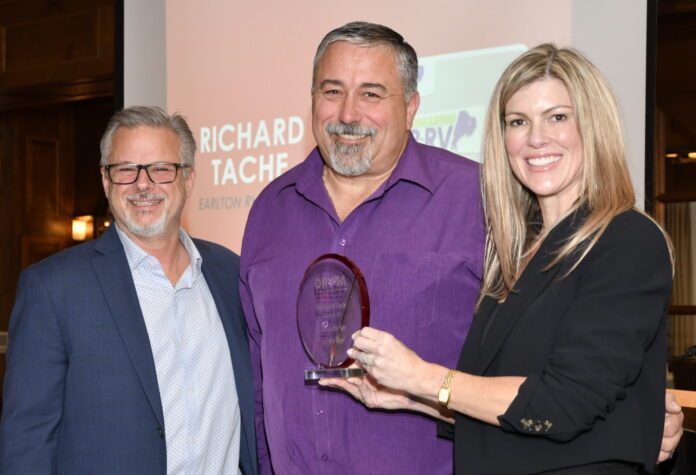 John Krohnert, left, and Natalie Conway, right, present the ORVDA RV Dealer of the Year Award to Richard Tache.